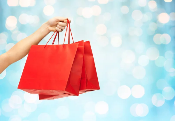 Close up de mão segurando sacos de compras vermelhos — Fotografia de Stock