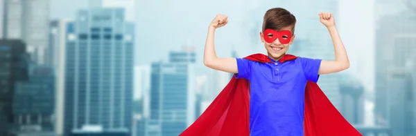 Мальчик в красном супергеройском плаще и маске показывает кулаки — стоковое фото