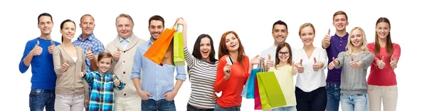 Gente feliz con bolsas de compras mostrando los pulgares hacia arriba — Foto de Stock