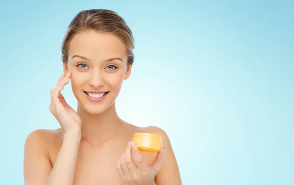 Feliz joven mujer aplicando crema a su cara —  Fotos de Stock