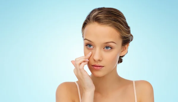 Mujer joven aplicando crema en su cara —  Fotos de Stock