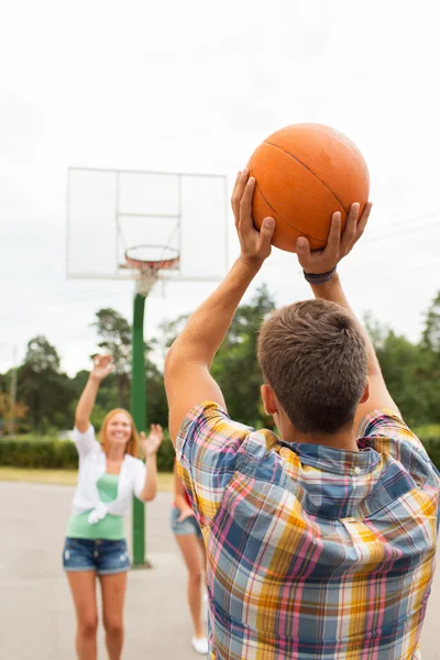 Groep gelukkig tieners spelen basketbal — Stockfoto