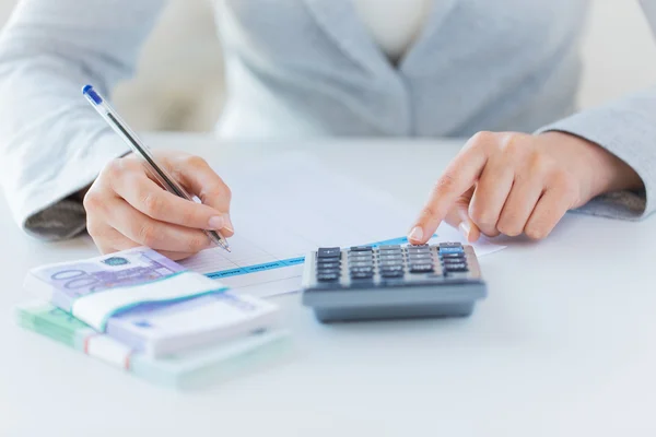 Fechar as mãos contando dinheiro com calculadora — Fotografia de Stock