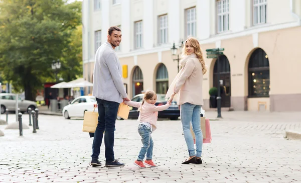 Família feliz com criança e sacos de compras na cidade — Fotografia de Stock