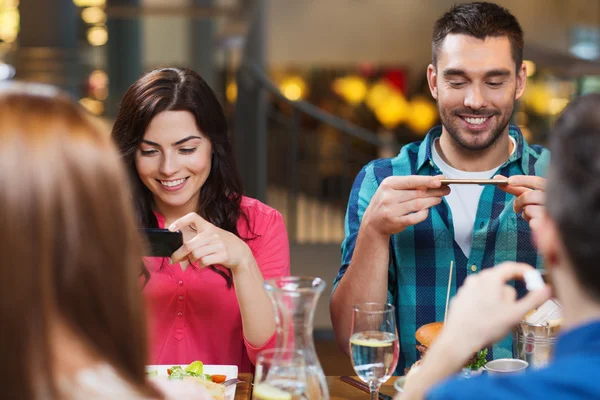 Happy friends taking picture of food at restaurant — Stock Photo, Image