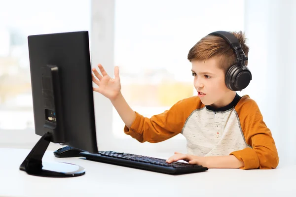 Jongen met computer en koptelefoon thuis — Stockfoto