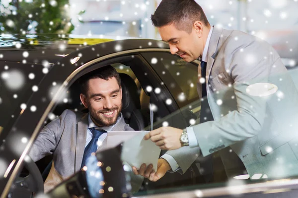 Šťastný muž s prodejci aut v autosalonu nebo salónek — Stock fotografie