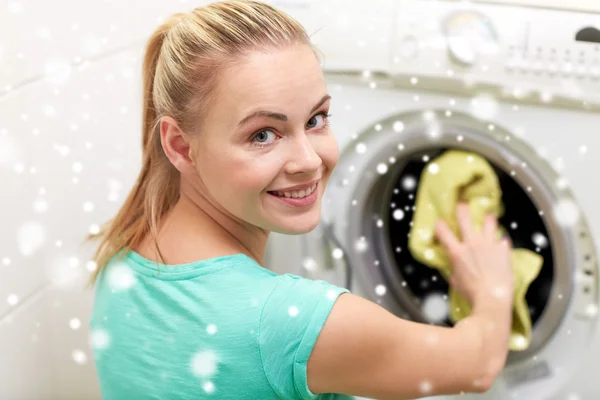 Mulher feliz colocando roupa na máquina de lavar em casa — Fotografia de Stock