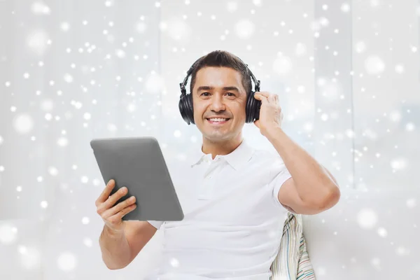 Sorrindo homem com tablet pc e fones de ouvido em casa — Fotografia de Stock