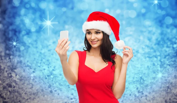 Kobieta w kapeluszu santa biorąc selfie przez smartphone — Zdjęcie stockowe