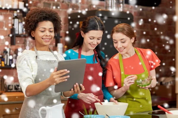Happy women with tablet pc cooking in kitchen — Stock Photo, Image