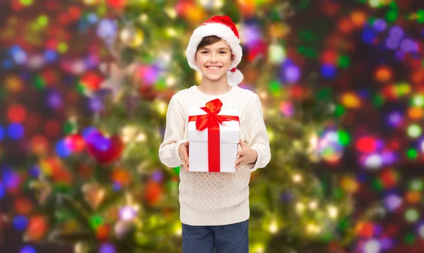 Sourire garçon heureux dans le chapeau de Père Noël avec boîte cadeau — Photo