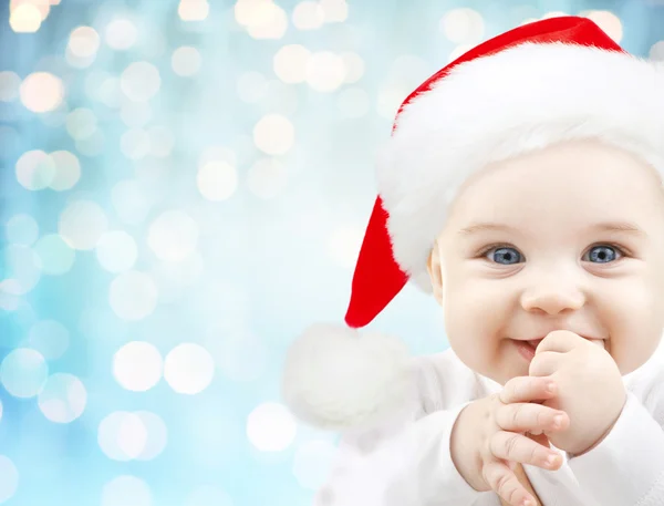 Bebê feliz em santa chapéu sobre luzes feriados azuis — Fotografia de Stock