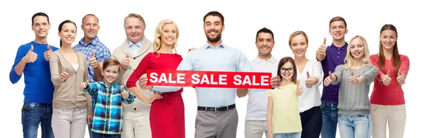 Happy people with red sale sign showing thumbs up — Stock Photo, Image