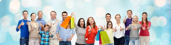 Gente feliz con bolsas de compras mostrando los pulgares hacia arriba — Foto de Stock