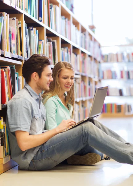 Happy students with laptop in library — Stock Photo, Image