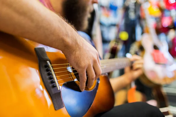 Close up of man playing guitar at music store — 图库照片