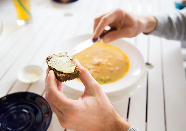 Close up of hands applying butter to bread — Stock Photo, Image