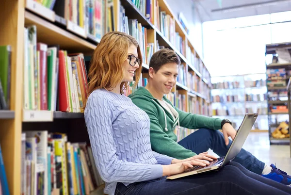 Happy students with laptop in library — Stock Photo, Image