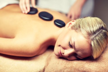 close up of woman having hot stone massage in spa clipart