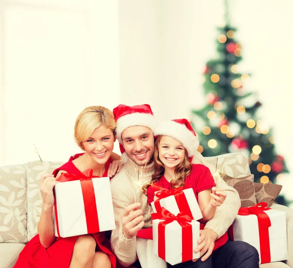 Lachende familie holding geschenkdozen en sparkles — Stockfoto