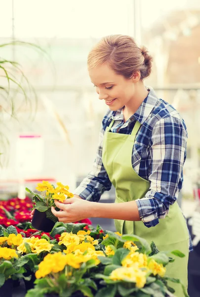 Glad kvinna med blommor i växthus — Stockfoto