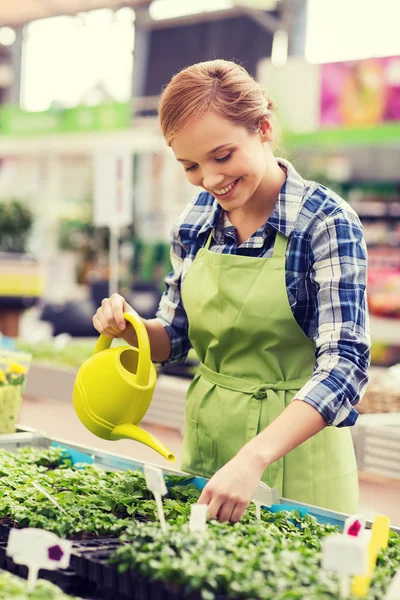 Happy woman with watering can in greenhouse — Stock Photo, Image