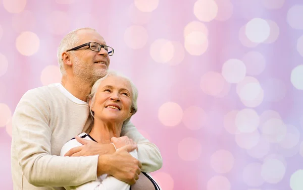 Happy senior couple hugging over lights background — Stock fotografie