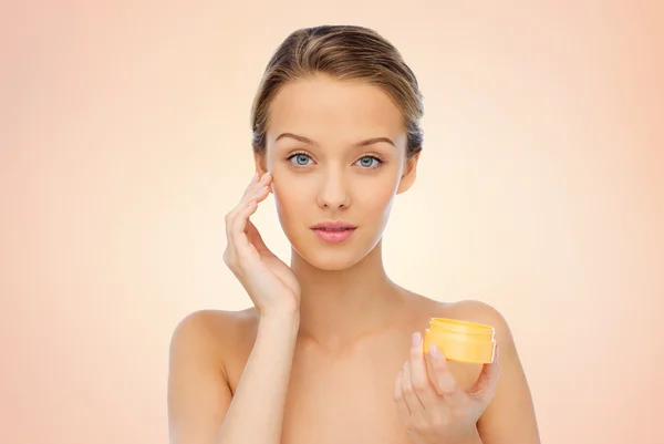 Mujer joven aplicando crema en su cara —  Fotos de Stock