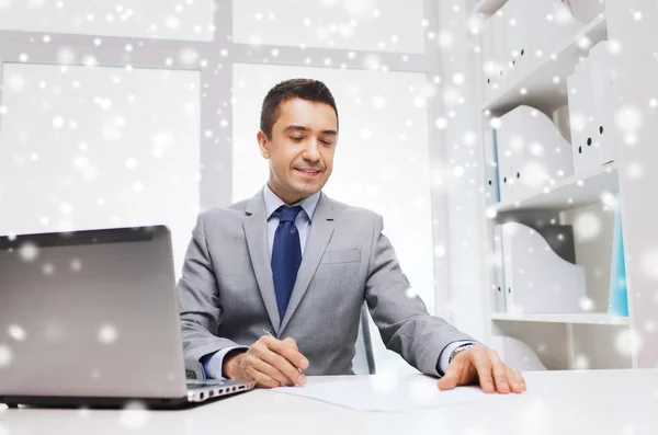Улыбающийся бизнесмен с ноутбуком и бумагами — стоковое фото