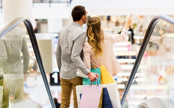 Feliz jovem casal com sacos de compras no shopping — Fotografia de Stock