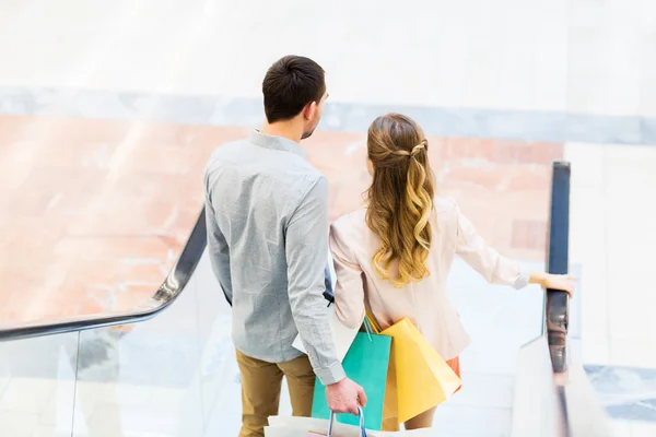 Feliz jovem casal com sacos de compras no shopping — Fotografia de Stock