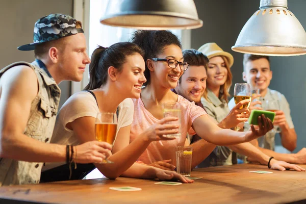 Счастливые друзья со смартфоном делают селфи в баре — стоковое фото