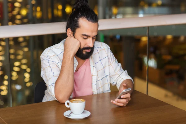 Человек со смартфоном и кофе в ресторане — стоковое фото