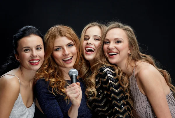 Mujeres jóvenes felices con micrófono cantando karaoke — Foto de Stock