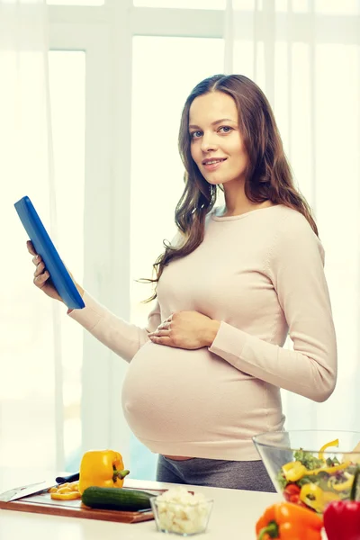 Mulher grávida feliz com tablet pc cozinhar alimentos — Fotografia de Stock