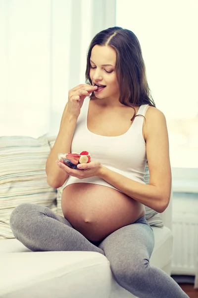 Gelukkig zwangere vrouw thuis eten van vruchten — Stockfoto