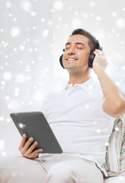 Hombre sonriente con tablet PC y auriculares en casa — Foto de Stock