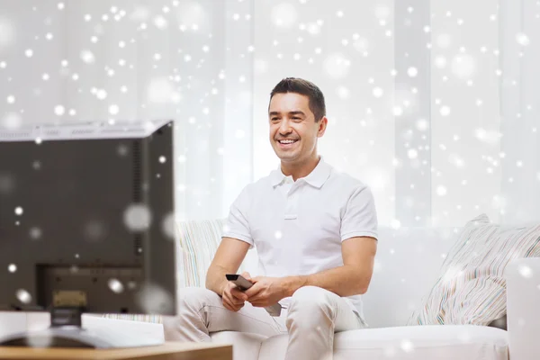 Uomo sorridente con telecomando guardando la tv — Foto Stock