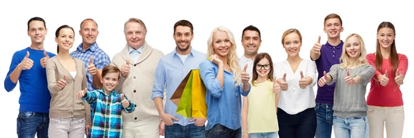 Gente feliz con bolsas de compras mostrando los pulgares hacia arriba — Foto de Stock