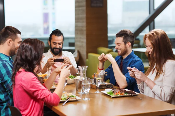Amigos felizes tirando fotos de comida no restaurante — Fotografia de Stock
