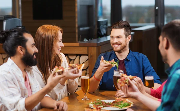 Amigos comendo pizza com cerveja no restaurante — Fotografia de Stock