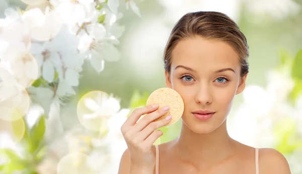 Mujer joven limpiando la cara con esponja exfoliante —  Fotos de Stock