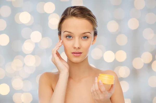 Mujer joven aplicando crema en su cara — Foto de Stock