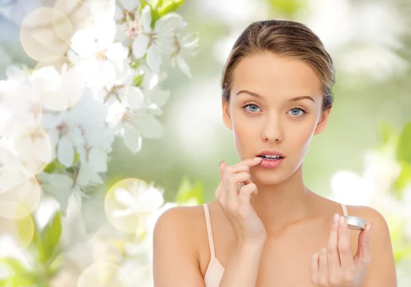 Young woman applying lip balm to her lips — Stock Photo, Image