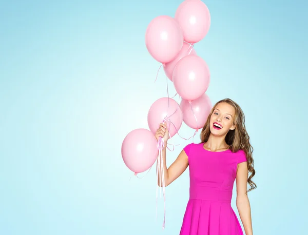 Счастливая молодая женщина с воздушными шарами над синим — стоковое фото