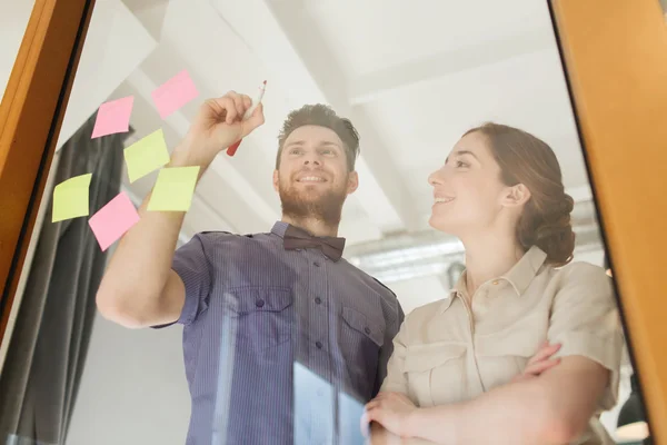 Glückliches kreatives Team, das auf leeres Büroglas schreibt — Stockfoto