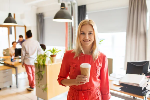 Femme créative heureuse avec tasse de café au bureau — Photo