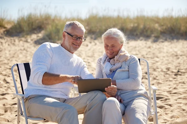 Felice coppia anziana con tablet pc sulla spiaggia estiva — Foto Stock