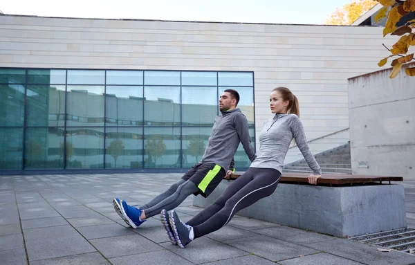 Пара делает трицепс погружения упражнения на открытом воздухе — стоковое фото